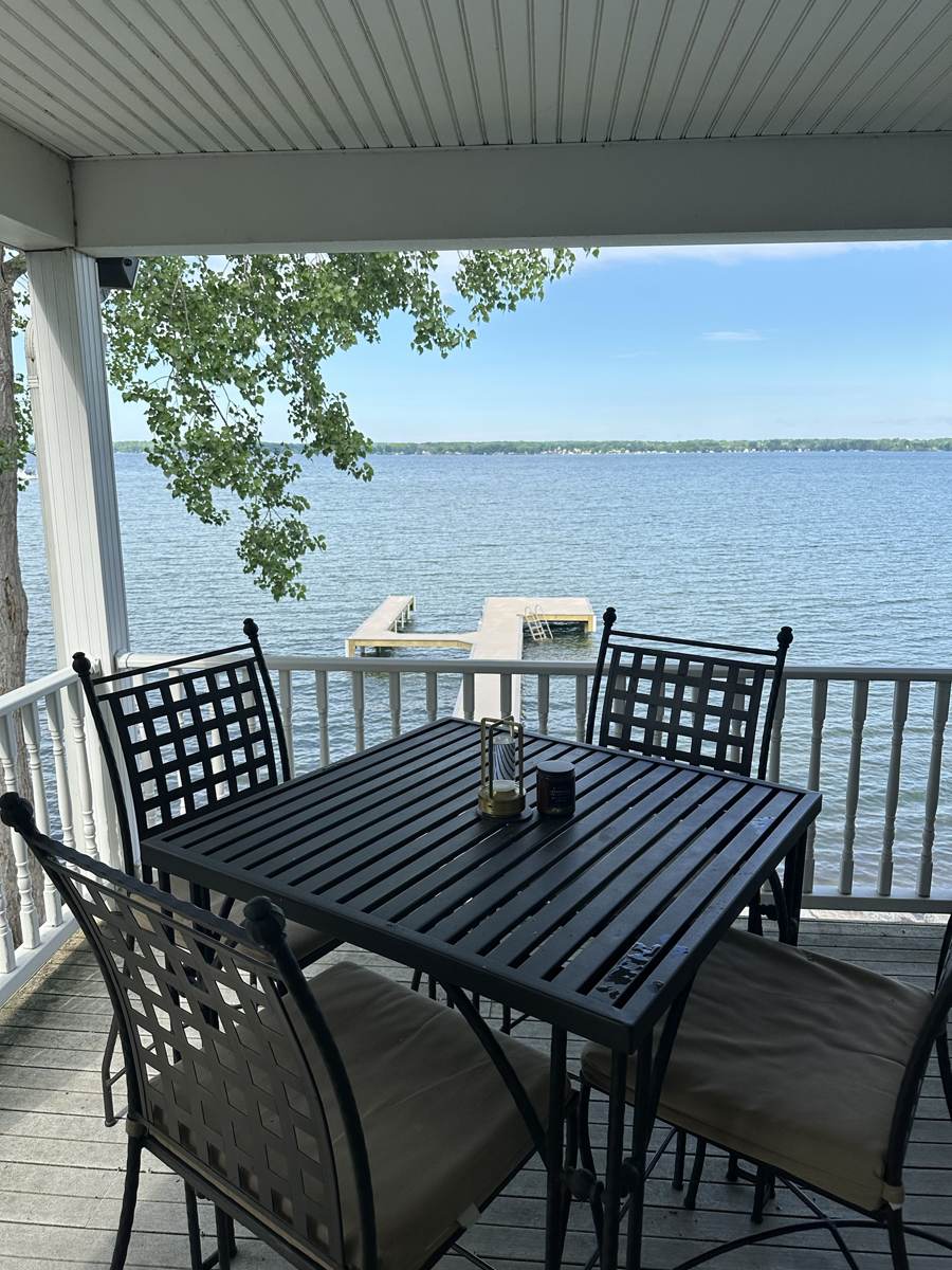 Covered porch dining with a view of the dock and lake