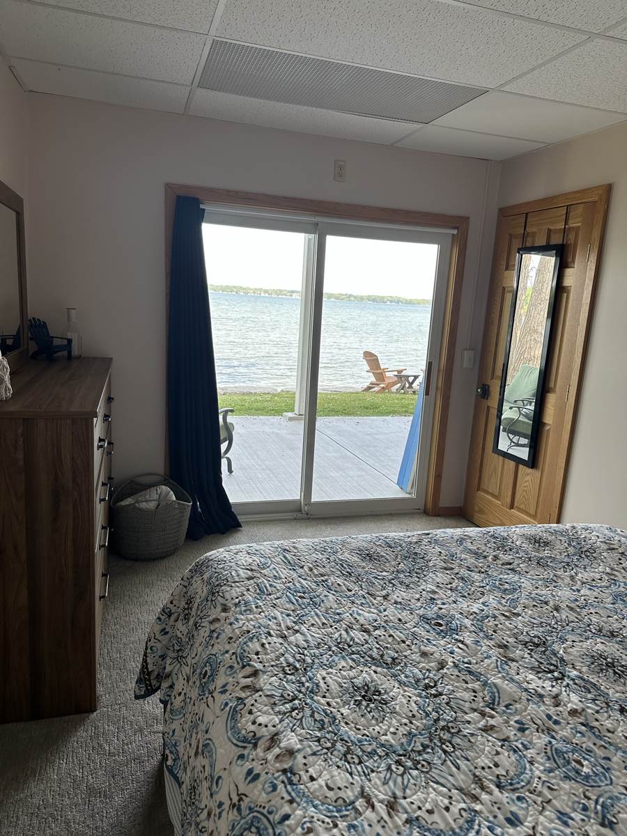 Bedroom with sliding doors out to the lawn and lake